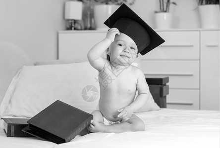 穿着尿布和沙发上毕业帽的婴儿照片图片