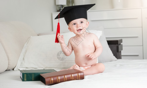 穿着黑色毕业帽尿布的滑稽小男孩肖像图片
