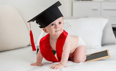 10个月大的小孩男穿着毕业帽子爬在床上图片