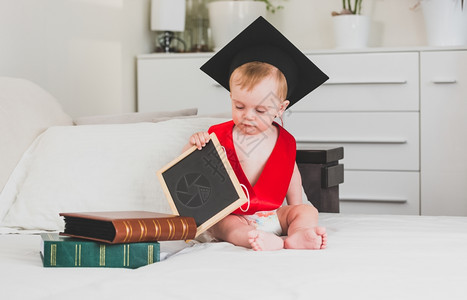 10个月大小孩男穿着黑色毕业帽子拿着一本书图片