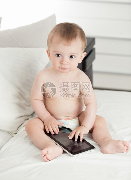 用数字平板电脑在床上拍摄可爱小男孩的画像图片