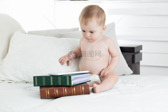 男婴使用数字桌子躺在堆积的书本上图片