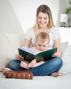 爱读书的孩子快乐的年轻母亲坐在客厅沙发上背景