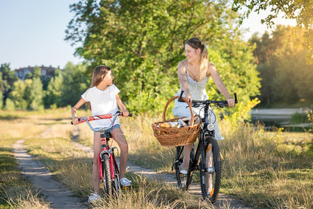 美丽的年轻母亲和女儿骑着自行车去野餐图片