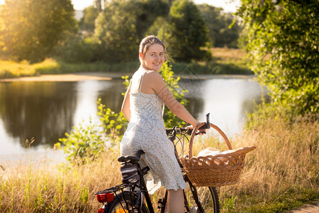 在湖边美丽的年轻母亲骑着自行车去野餐图片