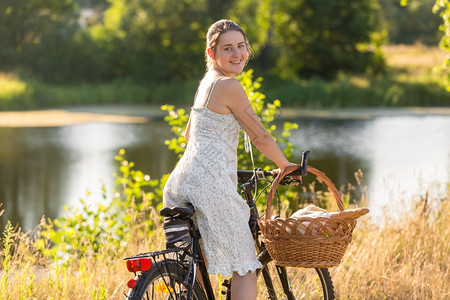 在湖边美丽的年轻母亲骑着自行车去野餐图片