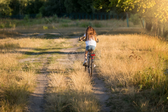 年轻妇女在草地的泥土路上骑自行车图片
