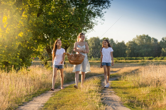 美丽的年轻母亲与两个女儿一起散步野餐图片