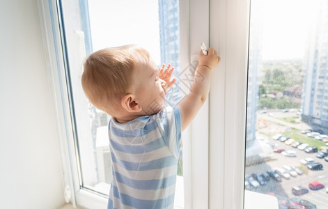 婴儿有危险男孩拉着窗户的把手图片