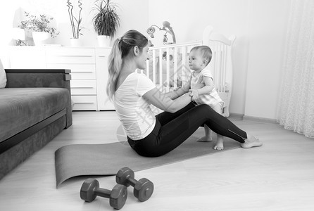 年轻快乐母亲与男孩一起在地板上运动的黑白画面图片
