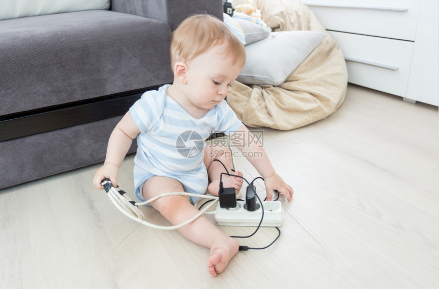 可爱的婴儿男孩玩电线和在地板上图片