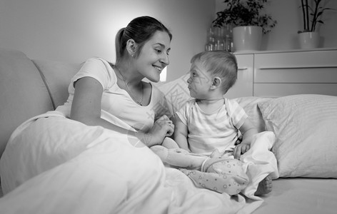 深夜在床上与婴儿交谈的幸福母亲黑白画像图片