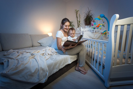 爱读书的孩子坐在母亲大腿上和睡觉前阅读书上背景