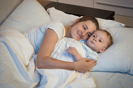 快乐的笑妈情感肖像晚上抱着婴儿在床睡觉图片
