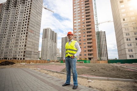 身穿硬帽和安全背心的年轻人站在建筑工地上图片