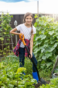 10岁的可爱女孩在花园工作用铲子挖土图片