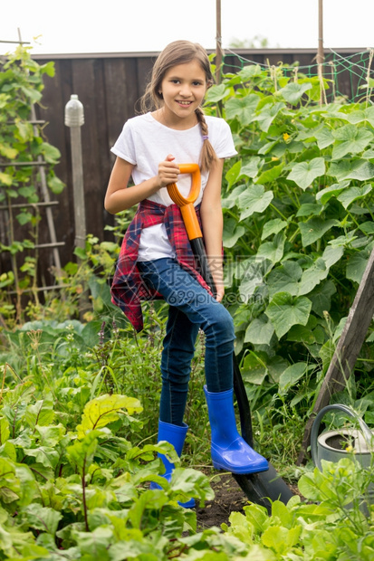 快乐的年轻女孩在花园用铲子工作图片