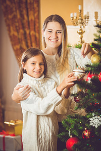 帮助妈装饰圣诞树的可爱笑女孩画像图片