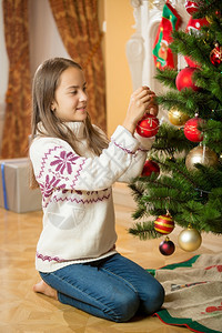 在家里装饰圣诞树的年轻女孩图片