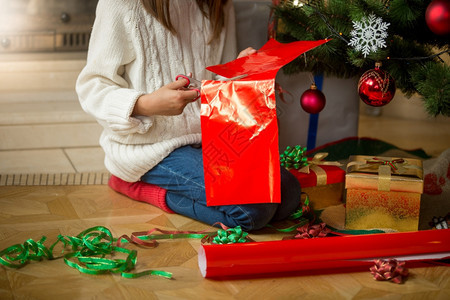 女孩在圣诞树下包装礼物的画面图片