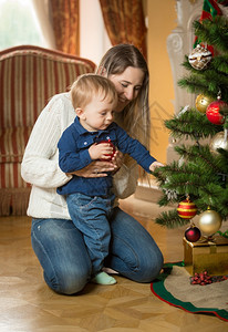 年轻母亲教她儿子如何装饰圣诞树图片