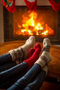 家庭穿着针织袜子在燃烧的壁炉中坐在小屋里图片