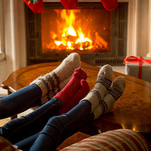 家庭在燃烧的壁炉上暖热毛绒袜子贴近形象图片