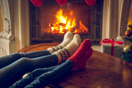 在小屋壁炉暖化的羊绒袜子中女和脚的近形象图片
