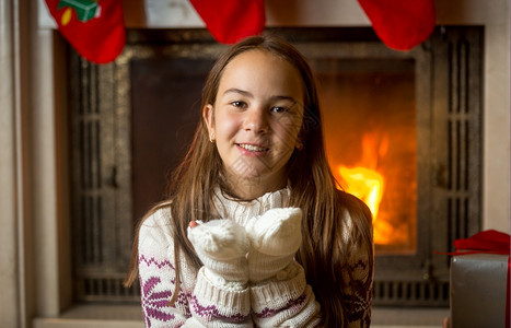 穿着羊毛衫和坐在燃烧壁炉的手套漂亮女孩肖像图片