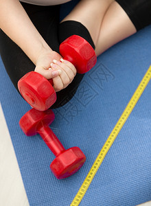 女在健身垫上锻炼和举起红色哑铃的特拍照片图片