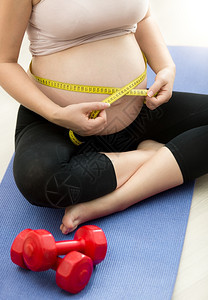 孕妇坐在健身垫子上测量腹部图片