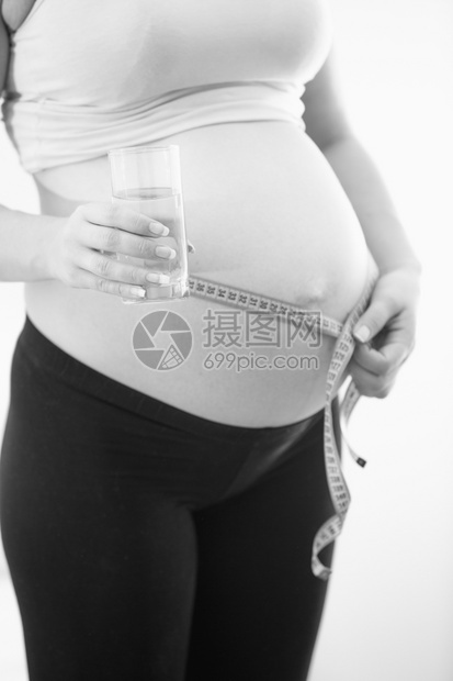 紧闭的黑白孕妇照片拿着杯水和大肚子测量图片