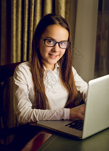 使用笔记本电脑白衬衫和眼镜的漂亮女学生肖像图片