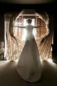 高雅的年轻新娘在酒店房间开窗帘图片