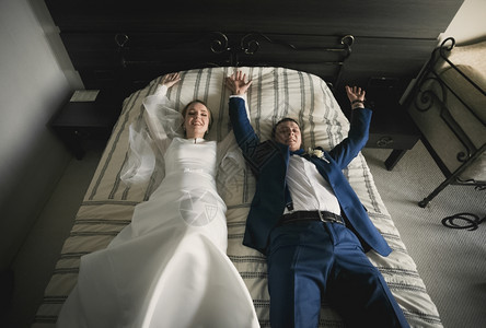 躺在酒店房间床上的幸福新娘和郎的肖像图片
