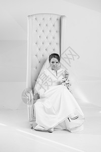 黑白一拍的优雅新娘在工作室的白色扶手椅上摆着图片