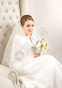 高雅新娘的肖像白玫瑰坐在工作室的椅子上图片