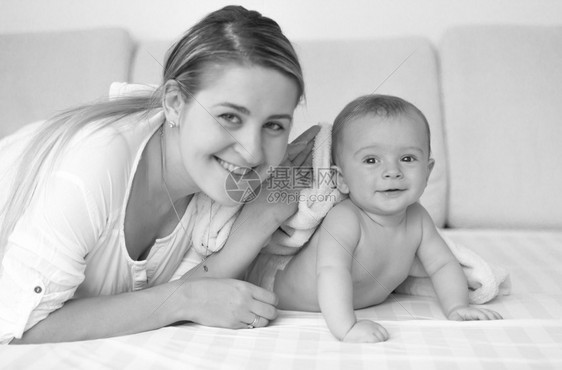 和6个月大的婴儿一起在床上放松的快乐母亲黑白像图片