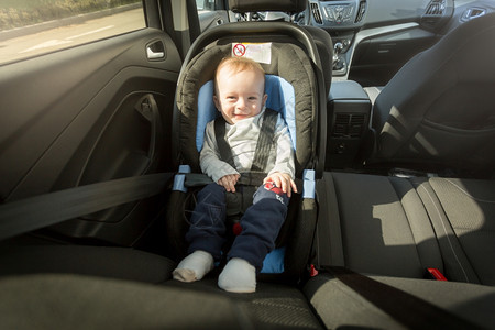 快乐笑的男孩婴儿在童安全汽车座位上摆着图片