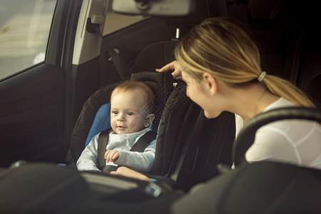 坐在车前座椅上汽车的母亲和婴儿男孩的托面肖像画图片