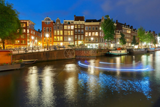 阿姆斯特丹运河Prinsengracht荷兰夜间有典型的荷兰码头房屋桥梁和光亮的船轨图片