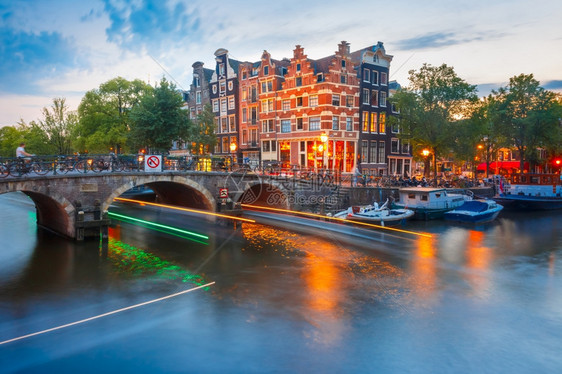 荷兰阿姆斯特丹运河桥梁和典型房屋船只和光亮的轨图片