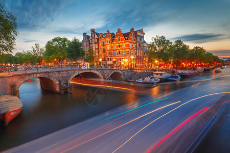 荷兰阿姆斯特丹运河桥梁和典型房屋船只和光亮的轨图片