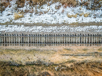 带杂草和积雪的单一铁路轨迹的空中观察图片