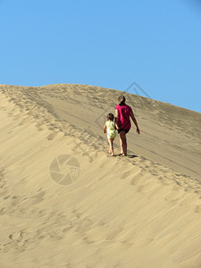 母亲和女儿在沙丘上行走图片