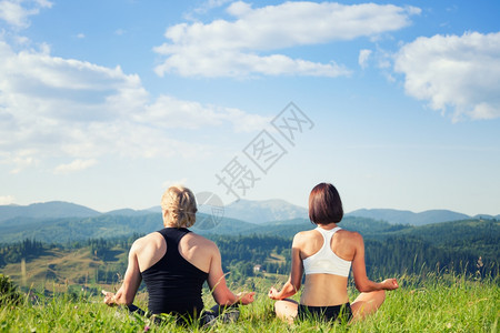 美丽的青年男女在夏季草原上做瑜伽锻炼冥想图片