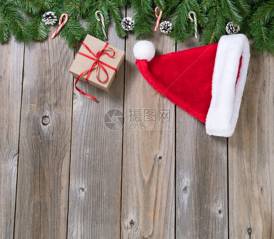 圣诞假日木背景配有Fir树枝圣诞帽和构成上界的礼品盒图片