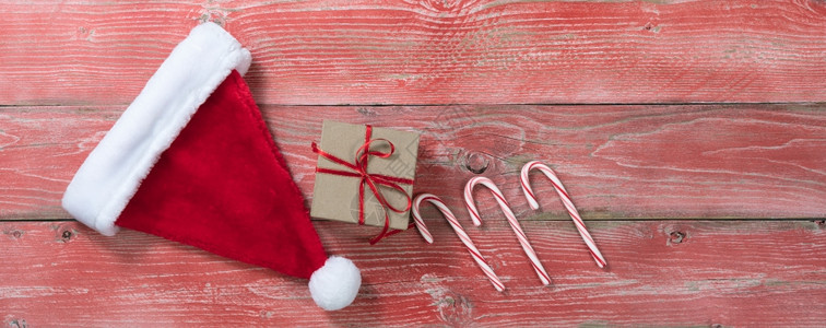 带有礼品盒圣诞树帽和糖果甘蔗的圣诞概念有条不紊红色木质背景带有复制空间的覆盖视图图片