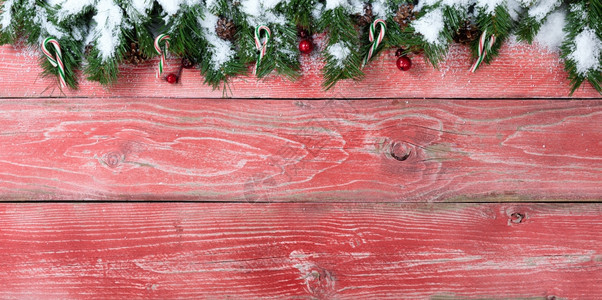 用于圣诞节概念的有雪花枝甘蔗红莓和松果的色木质背景上面有复制空间图片
