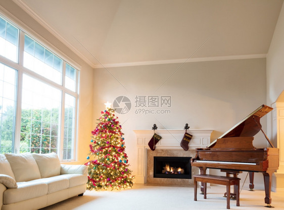 圣诞树在客厅里明亮的白天烧着壁炉和大钢琴图片